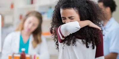 Girl sneezing into her arm