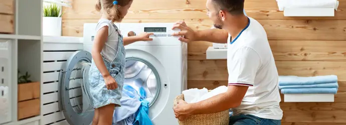 Father and child daughter doing laundry together in a fun kids laundry time