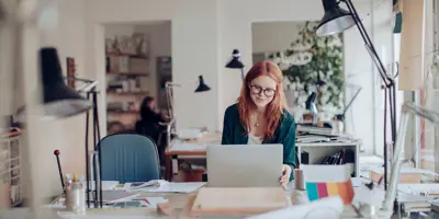 A woman working in her laptop sitting at her desk