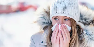 Woman in the snow blowing her nose