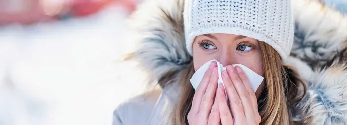 Woman in the snow blowing her nose