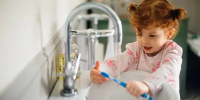 A mother helping her daughter and son washing their hands in the kitchen