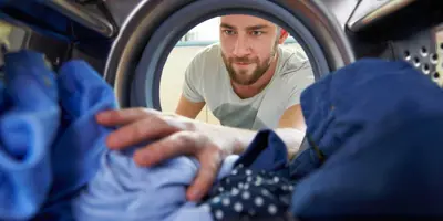 Man reaching for clothes inside the washing machine