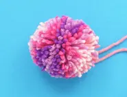 A wool pom pom made using wool of different pink shades.