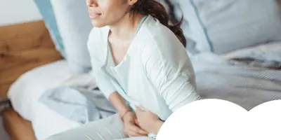 Woman sitting on her bed with abdominal pain