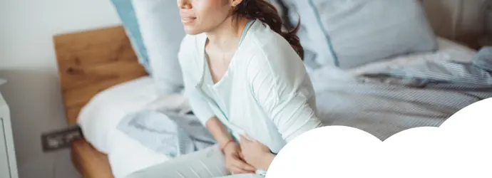 Woman sitting on her bed with abdominal pain